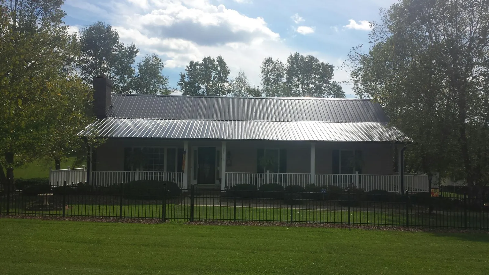 Gray metal roof on a brick ranch with a full width front porch — Gutter Guard Installation work by our crew in Davis Junction